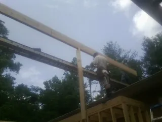 Carpenter setting a ridge beam over a new addition frame — Ice Dam Removal by Roofing Brothers in Commodore