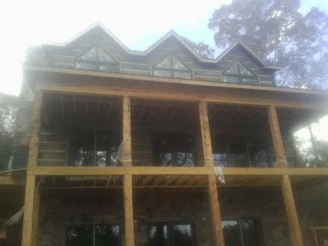 Dormers and porch framing on a large log home under construction — Roof Coating work by our crew in Commodore