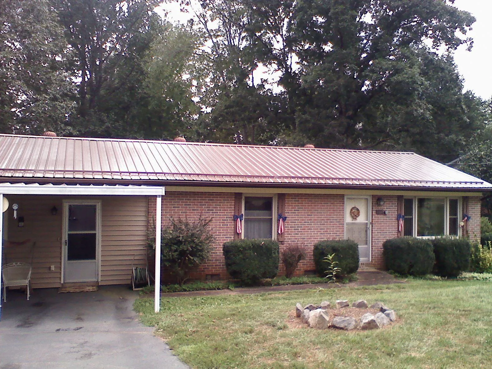 Bronze metal roof and carport on a brick ranch home — Roof Repair work by our crew in Commodore