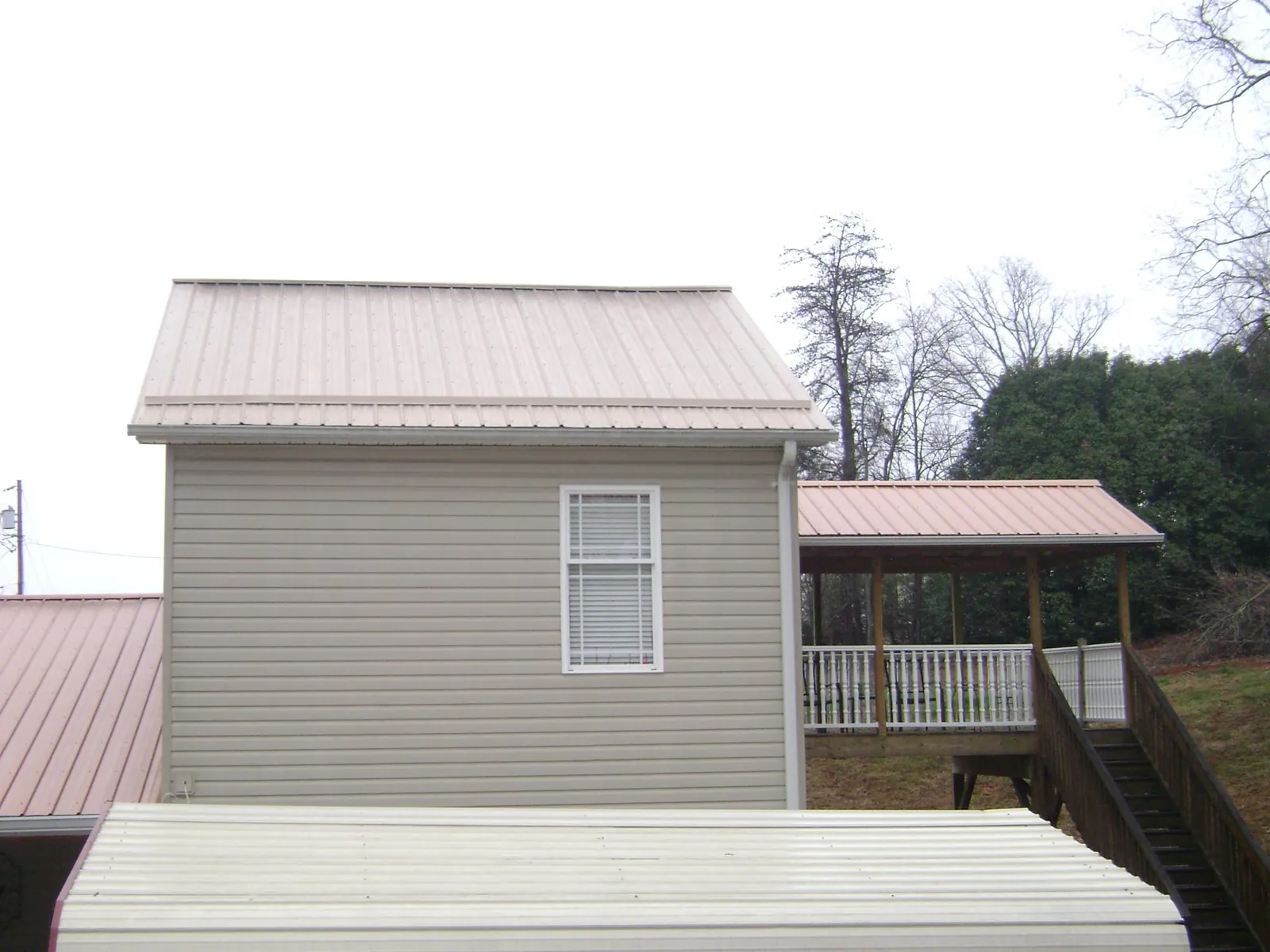 Tan metal roofs on a two story addition and attached porch, from a Roof Replacement job in Commodore