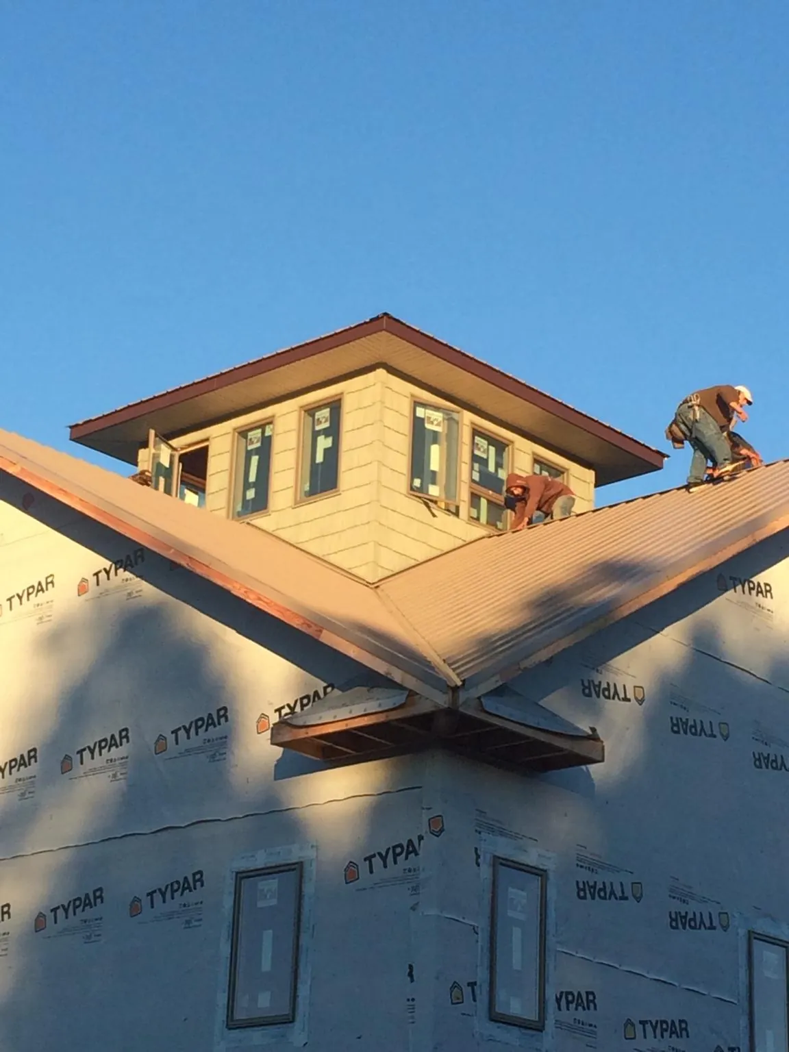 Roofers working around a rooftop cupola on a new metal roof at sunset — Roof Waterproofing in Commodore by Roofing Brothers